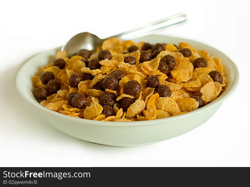 Cornflakes, cocoa balls and spoon in a bowl isolated on white. Cornflakes, cocoa balls and spoon in a bowl isolated on white.