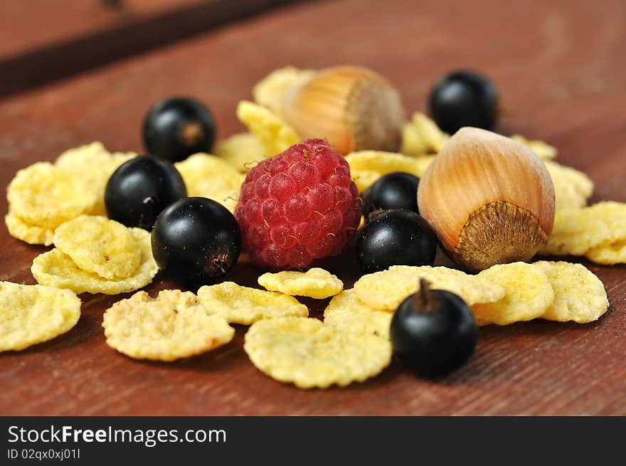 The corn flakes with berries on the wooden background. The corn flakes with berries on the wooden background