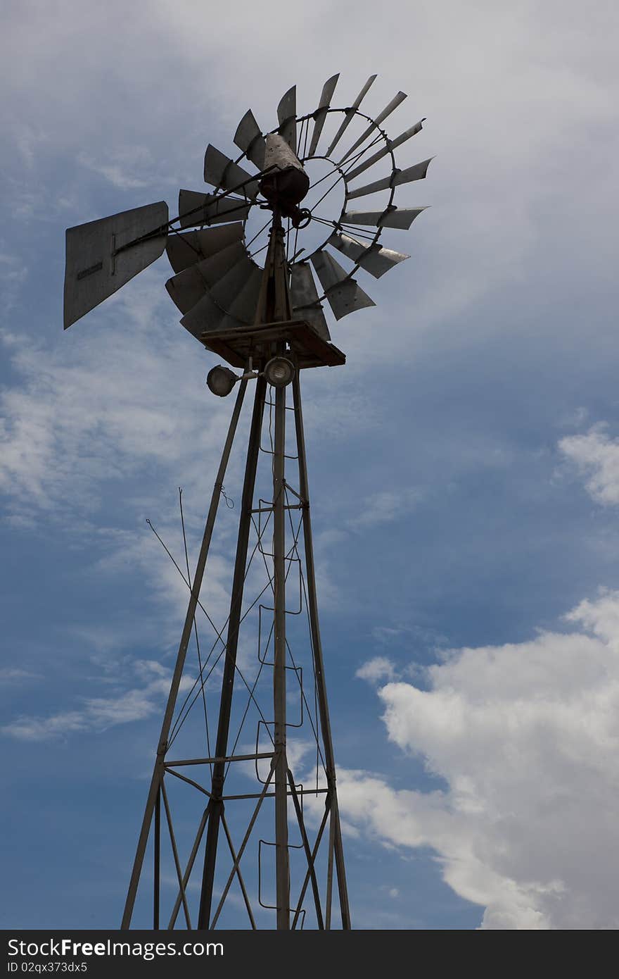 Rural Windmill Backlit Against Partly Cloudy Sky