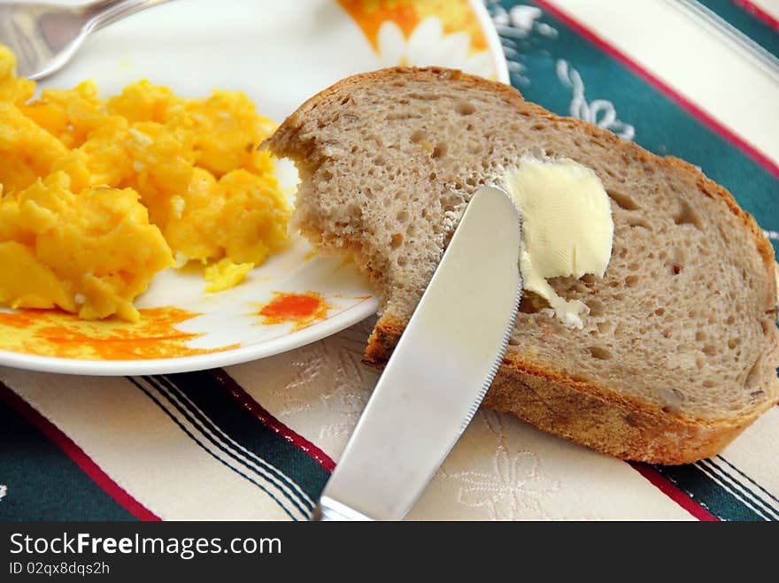 Knife on brown bread with butter and scrambled eggs served on table. Knife on brown bread with butter and scrambled eggs served on table