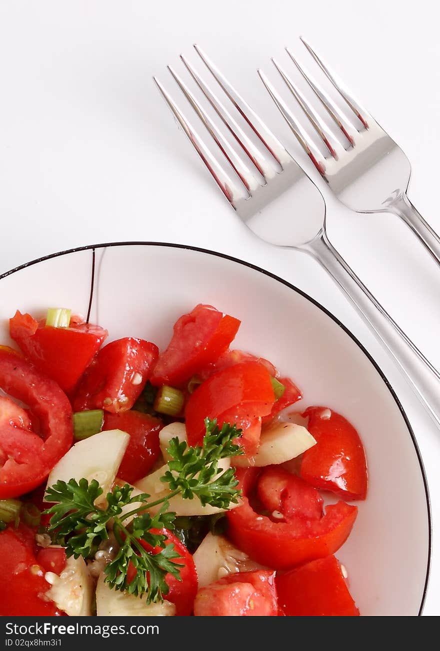 Red tomato and parsley salad with silver forks