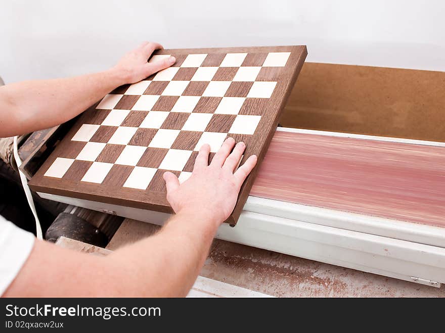 Carpenter working on an electric buzz saw cutting some chess boards