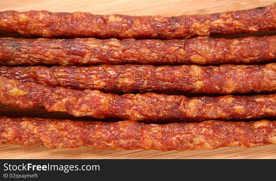 Smoked sausages on a wooden background in close up. Smoked sausages on a wooden background in close up