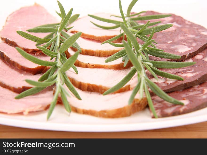 Plate of assorted cold cuts (ham, sirloin, headcheese) decorated with rosemary