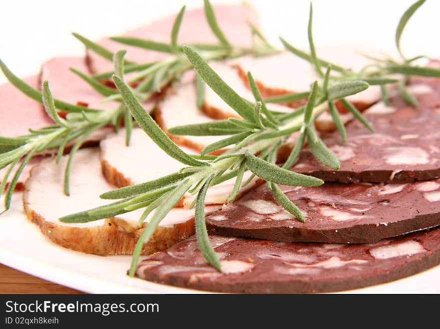 Plate of assorted cold cuts (ham, sirloin, headcheese) decorated with rosemary