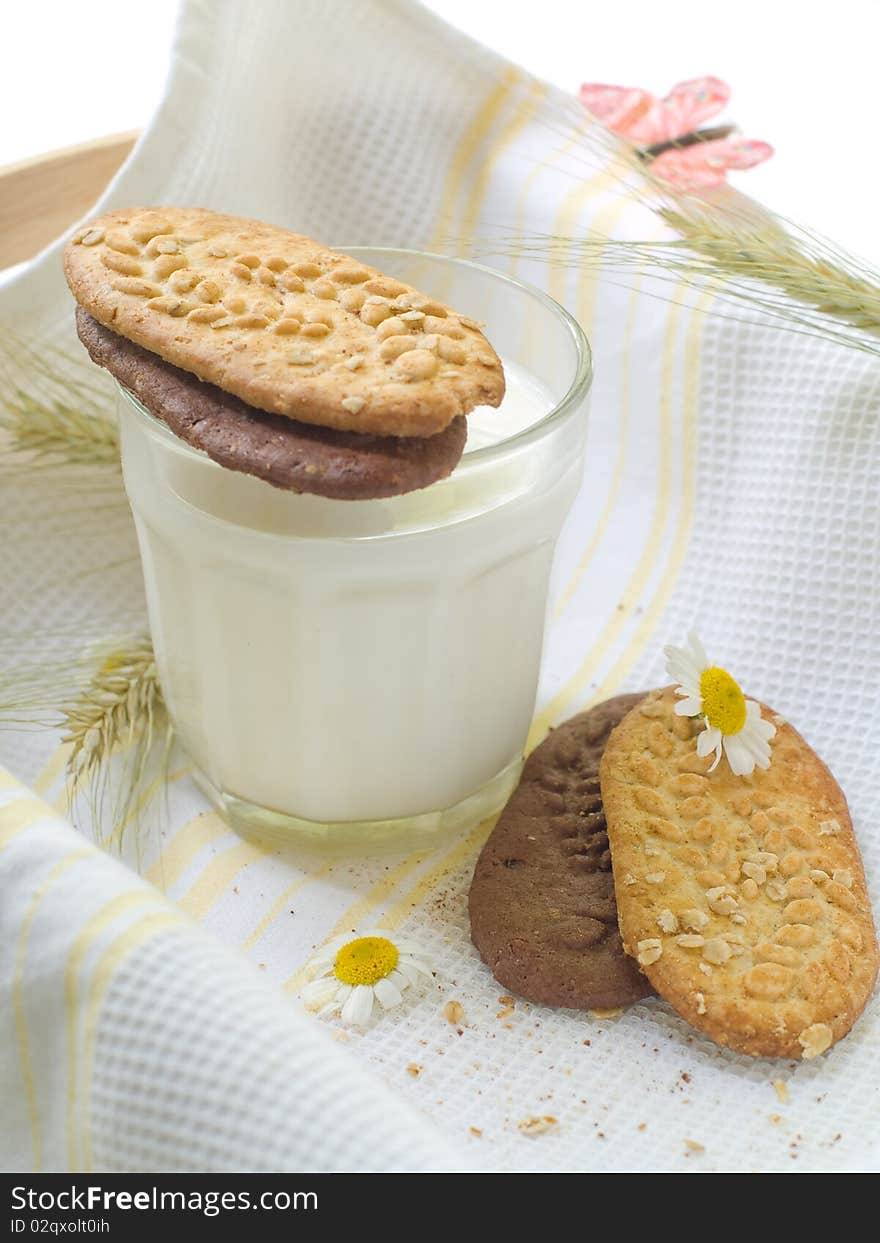 Glass of milk and cookies on light kitchen towel