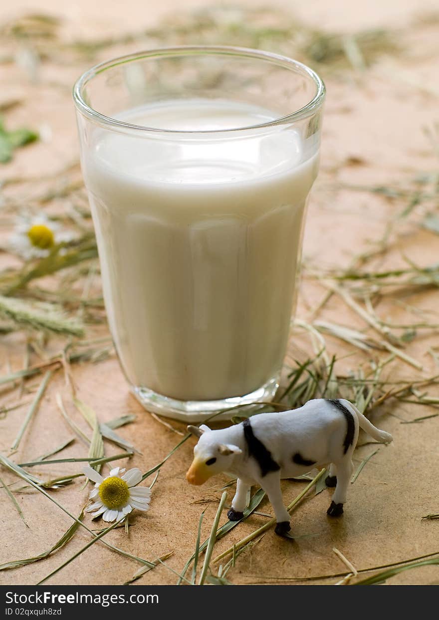 Milk glass on a board with toy cow