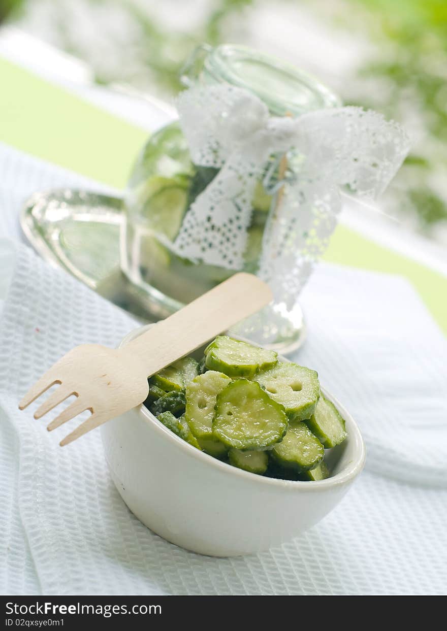 Fresh salted cucumber in bowl on kitchen towel