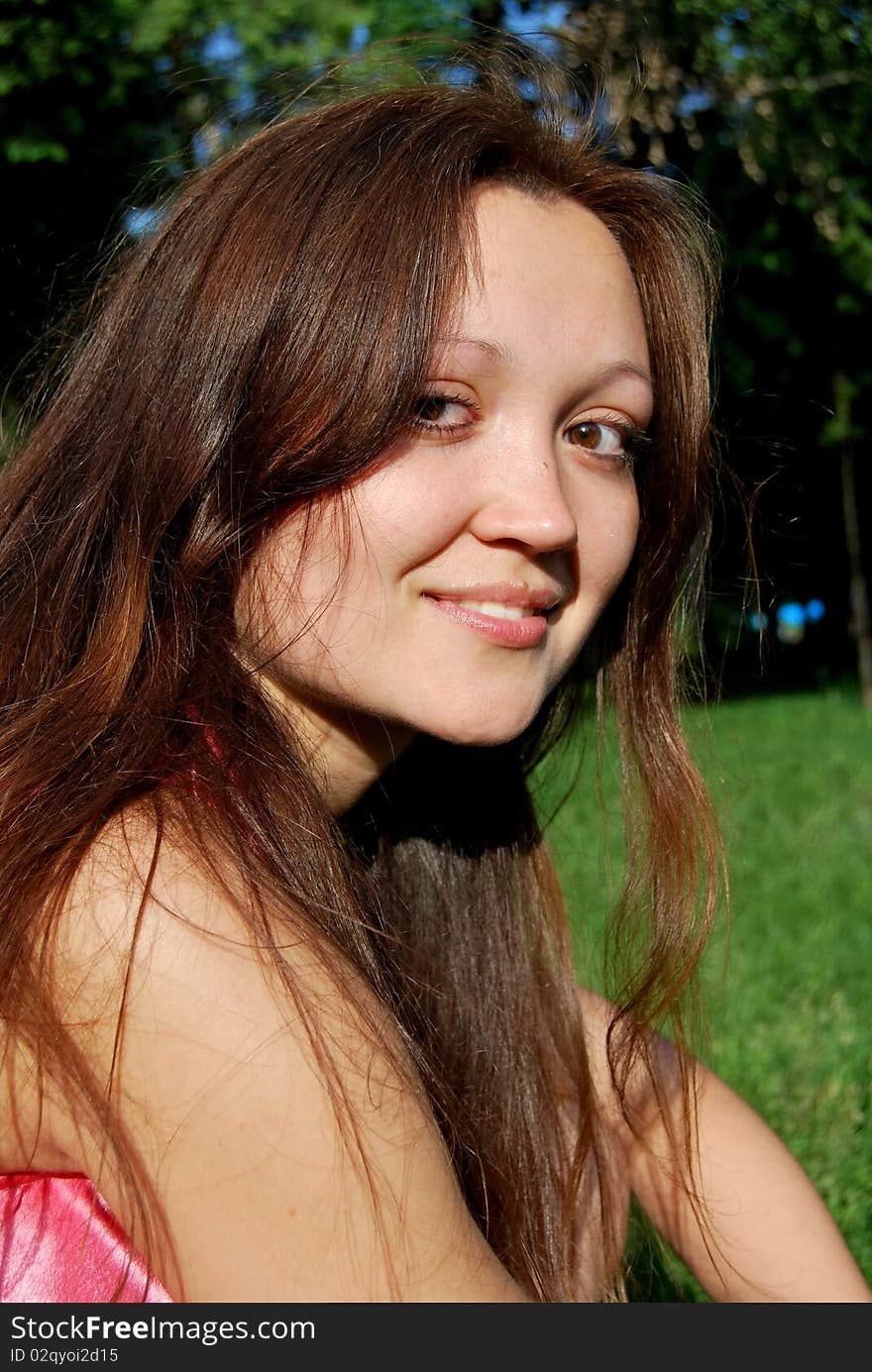 The happy young girl is wearing a pink dress in the park. The happy young girl is wearing a pink dress in the park