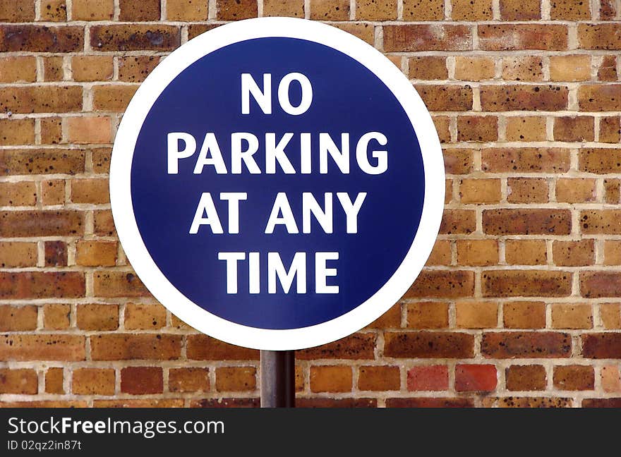 Round blue sign for no parking with a brickwall in the background