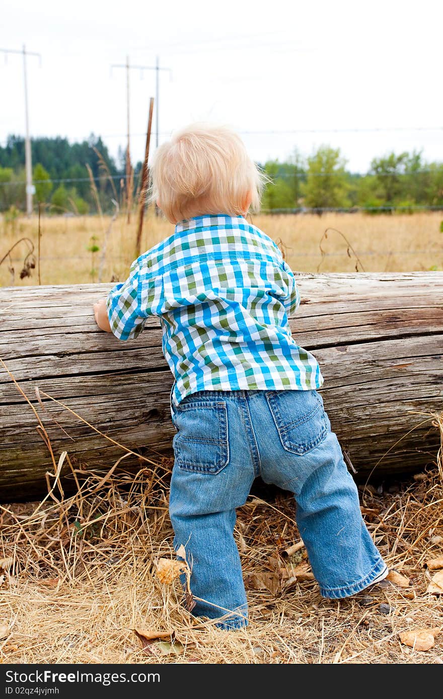 A young one year old kid in a rural field wearing a plaid shirt with blue eyes and blonde hair. A young one year old kid in a rural field wearing a plaid shirt with blue eyes and blonde hair.