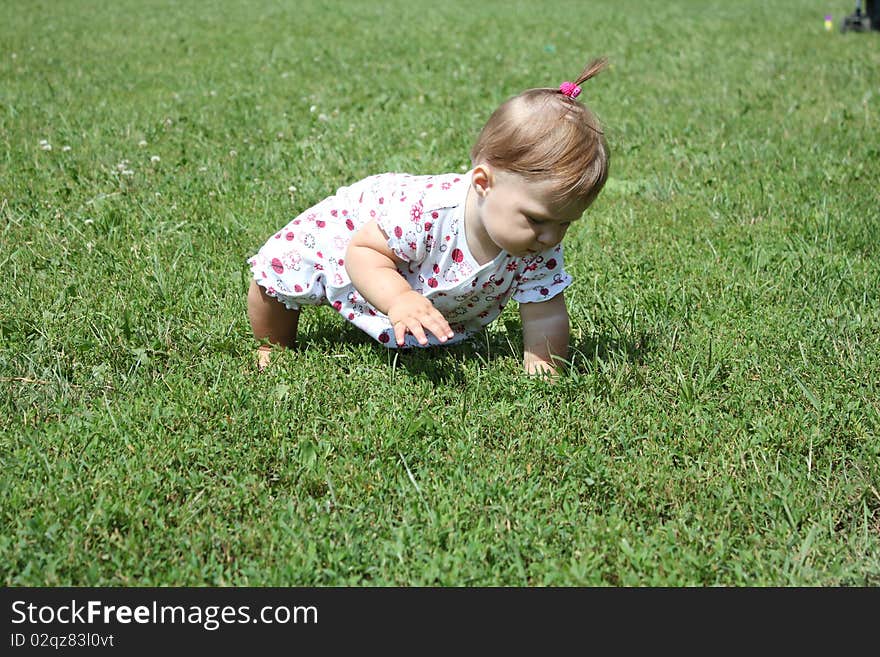 Child is sitting on the green grass