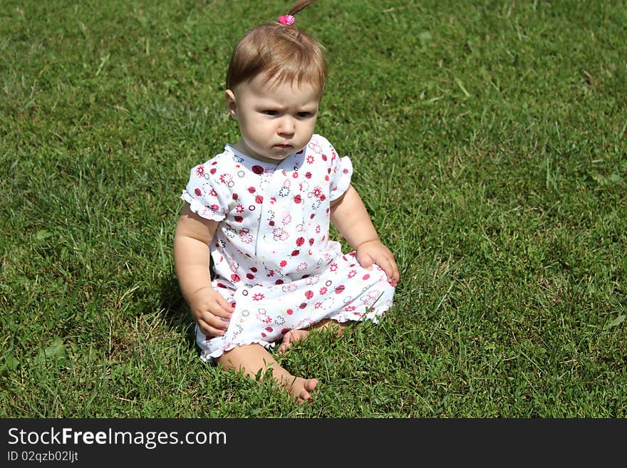 Child is sitting on the green grass