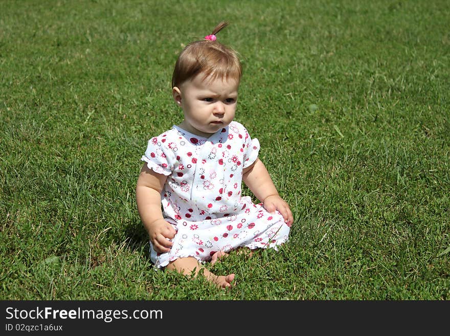 The child joyfully sits on a grass