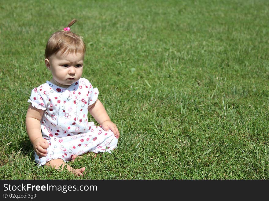 Child is sitting on the green grass