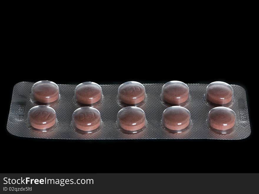 Closeup of a pack of brown pills isolated on black