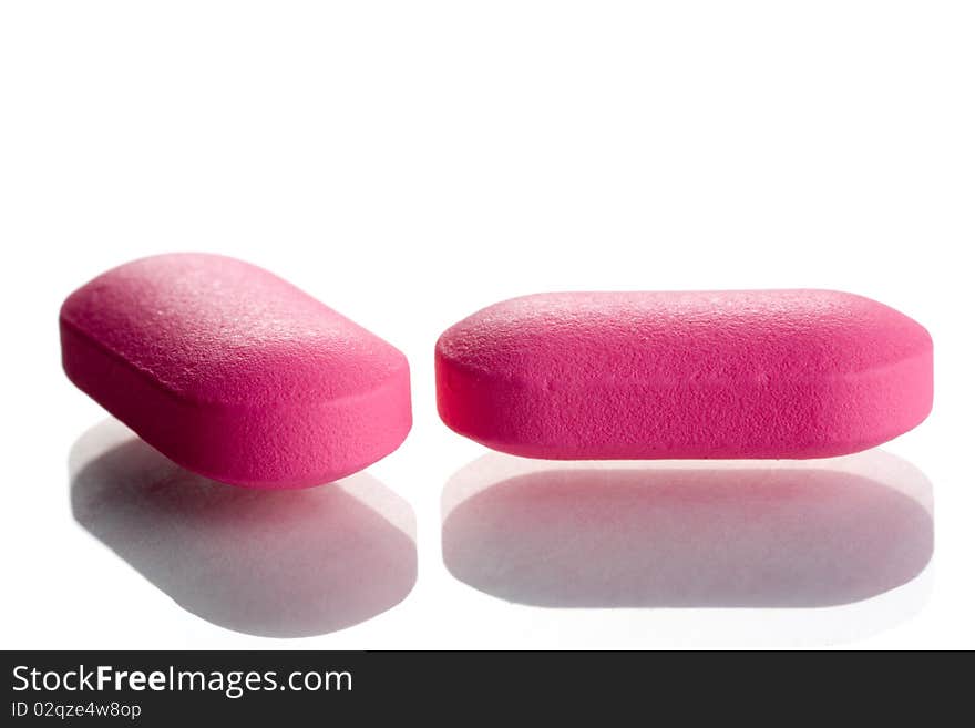 Extreme close-up of pink pills isolated on white background