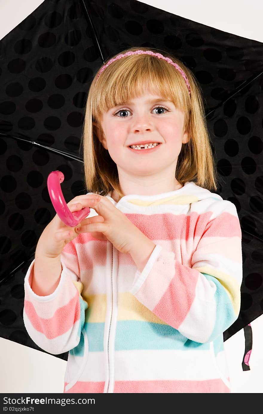 A vertical image of a pretty cute young girl with blonde hair and blue eyes standing holding her umbrella. A vertical image of a pretty cute young girl with blonde hair and blue eyes standing holding her umbrella