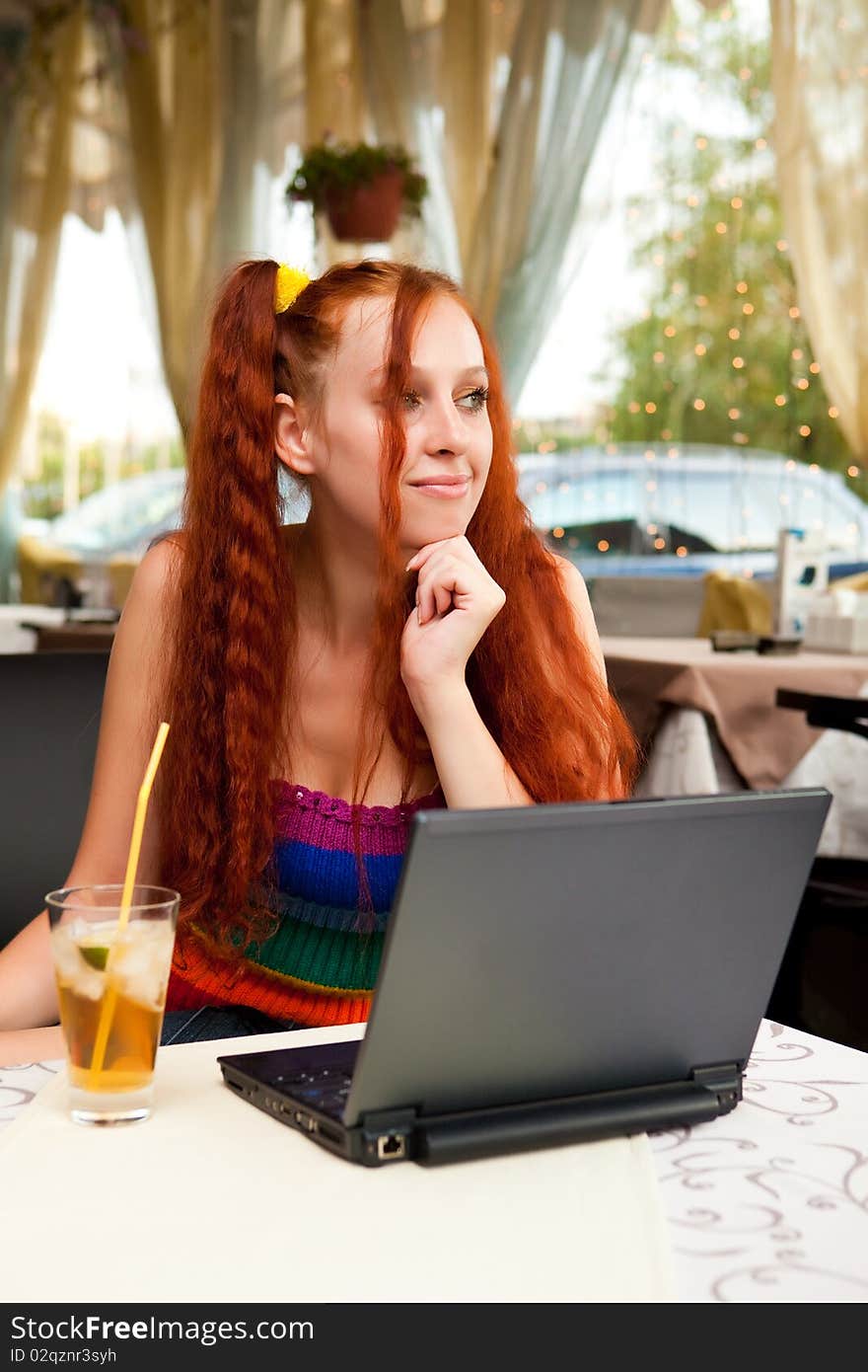 Girl with a cocktail and the laptop in cafe. Girl with a cocktail and the laptop in cafe