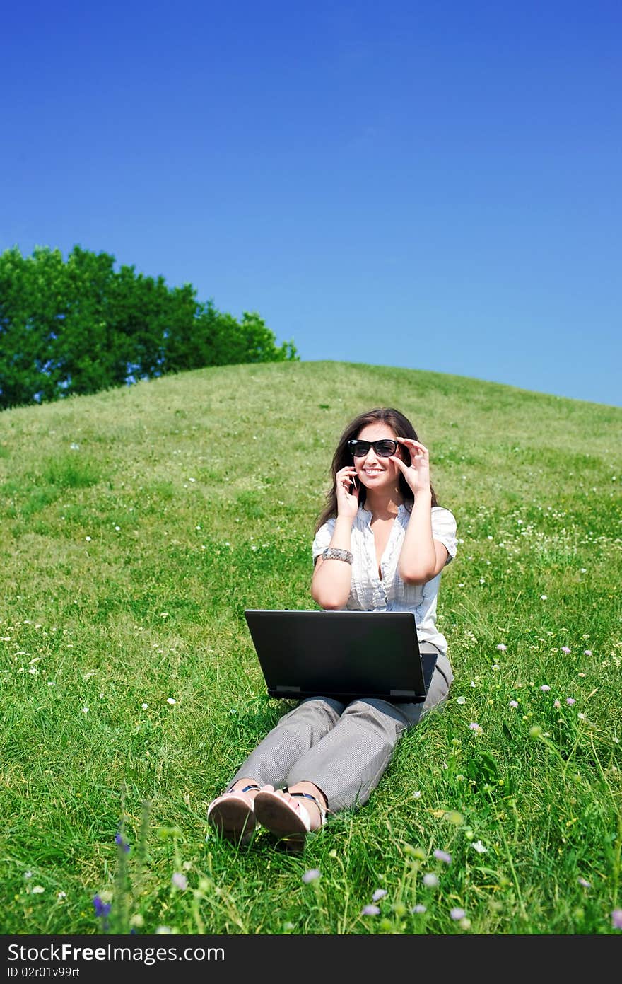 Woman with notebook and  phone sit on hill