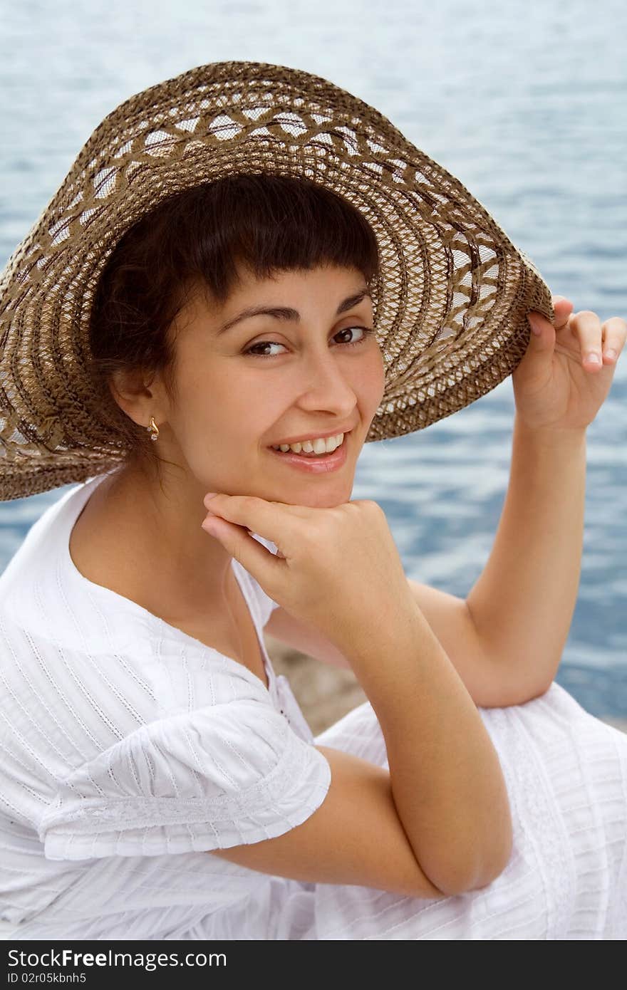 Happy young girl in the bonnet near the sea