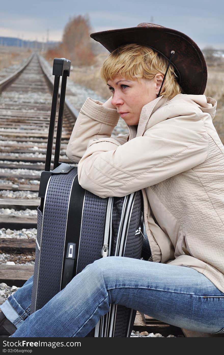 Respite on the railroad tracks, a woman pilgrim from the suitcase sitting in the image of the cowboy. Respite on the railroad tracks, a woman pilgrim from the suitcase sitting in the image of the cowboy