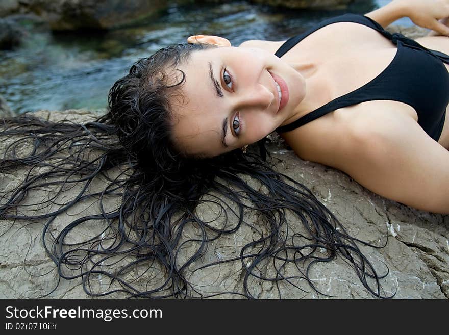 Pretty girl  lying  on the rock at the sea