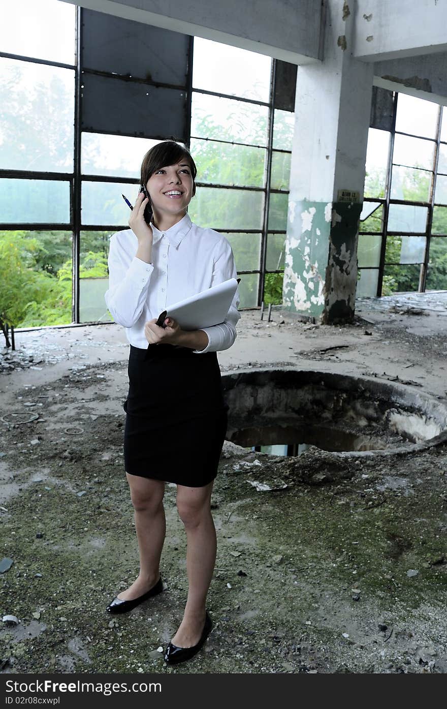 Young business woman talking on mobile phone about demolished building. Young business woman talking on mobile phone about demolished building