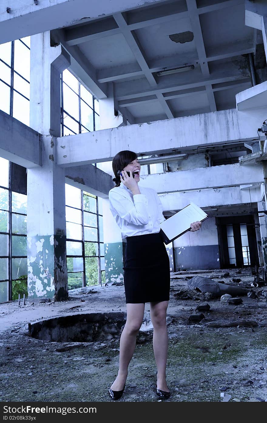 Young business woman talking on mobile phone about demolished building. Young business woman talking on mobile phone about demolished building