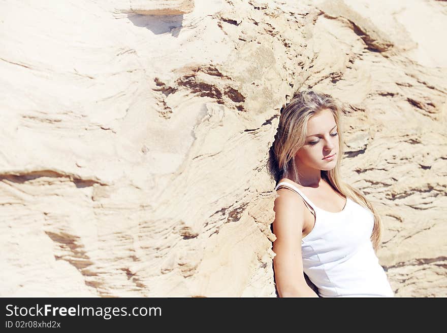 Young girl the blonde in jeans, against sand