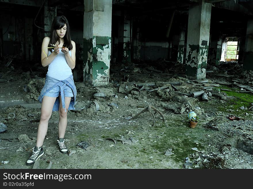 Caucasian young woman studying plant in devastated building. Caucasian young woman studying plant in devastated building