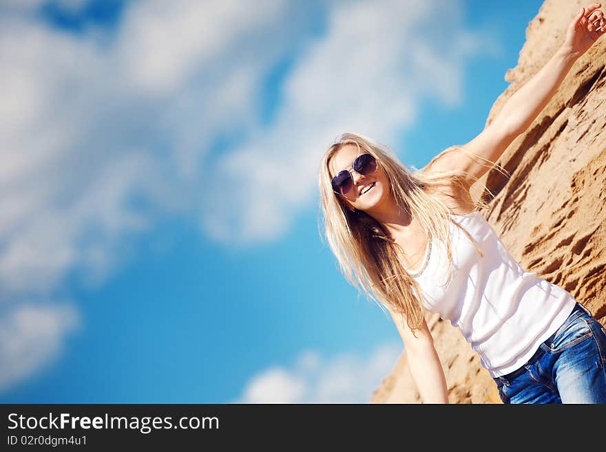 Young girl the blonde in jeans, against sand