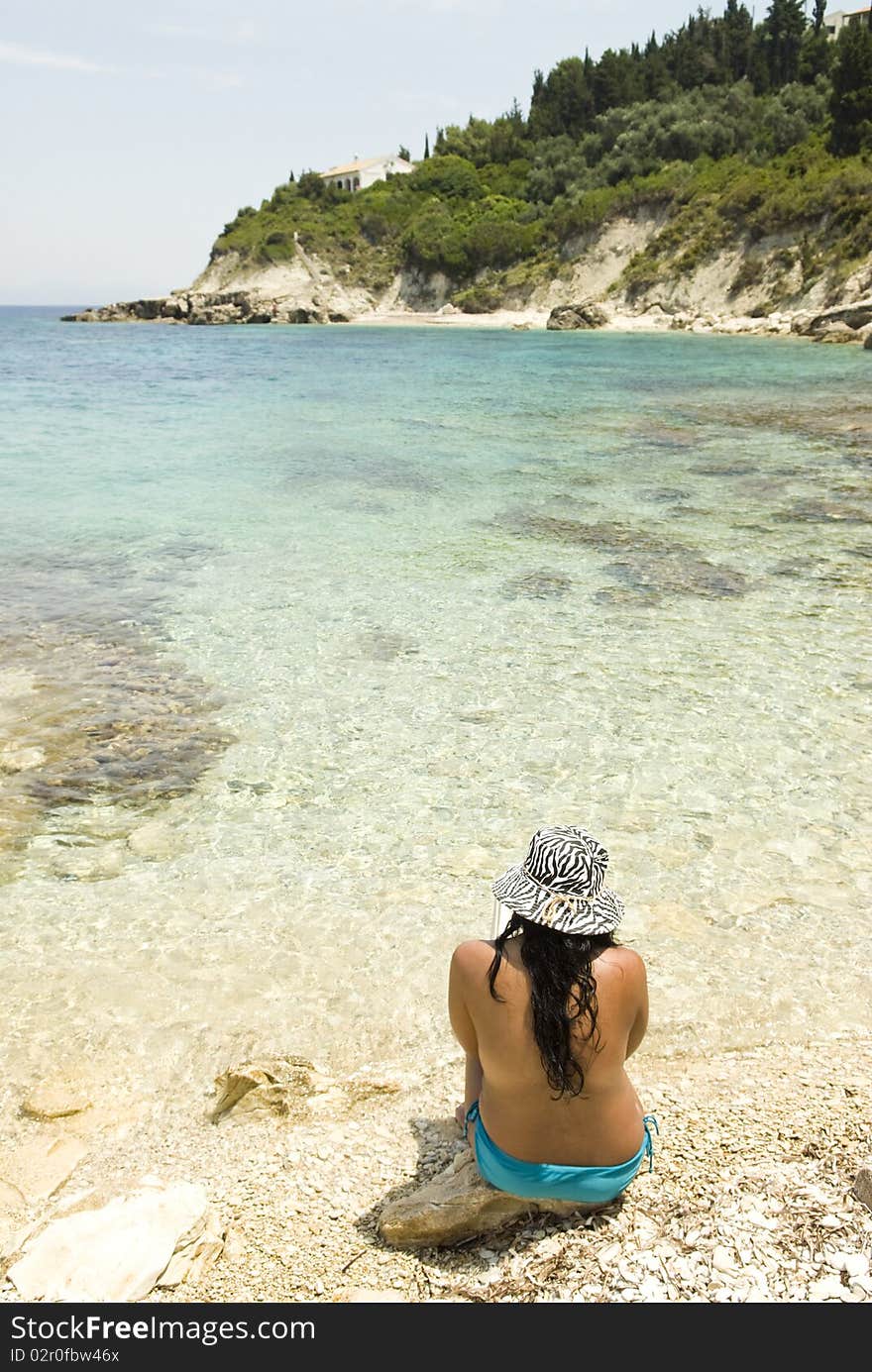 Asian woman sitting on a rocky beach enjoying the stunning view. Asian woman sitting on a rocky beach enjoying the stunning view.