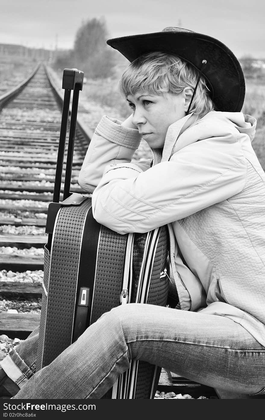 Respite on the railroad tracks, a woman pilgrim from the suitcase sitting in the image of the cowboy. Respite on the railroad tracks, a woman pilgrim from the suitcase sitting in the image of the cowboy