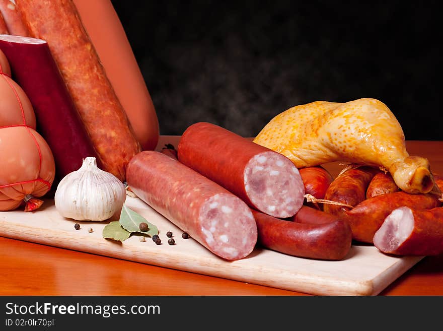 A variety of processed cold meat products, on a wooden cutting board. A variety of processed cold meat products, on a wooden cutting board.