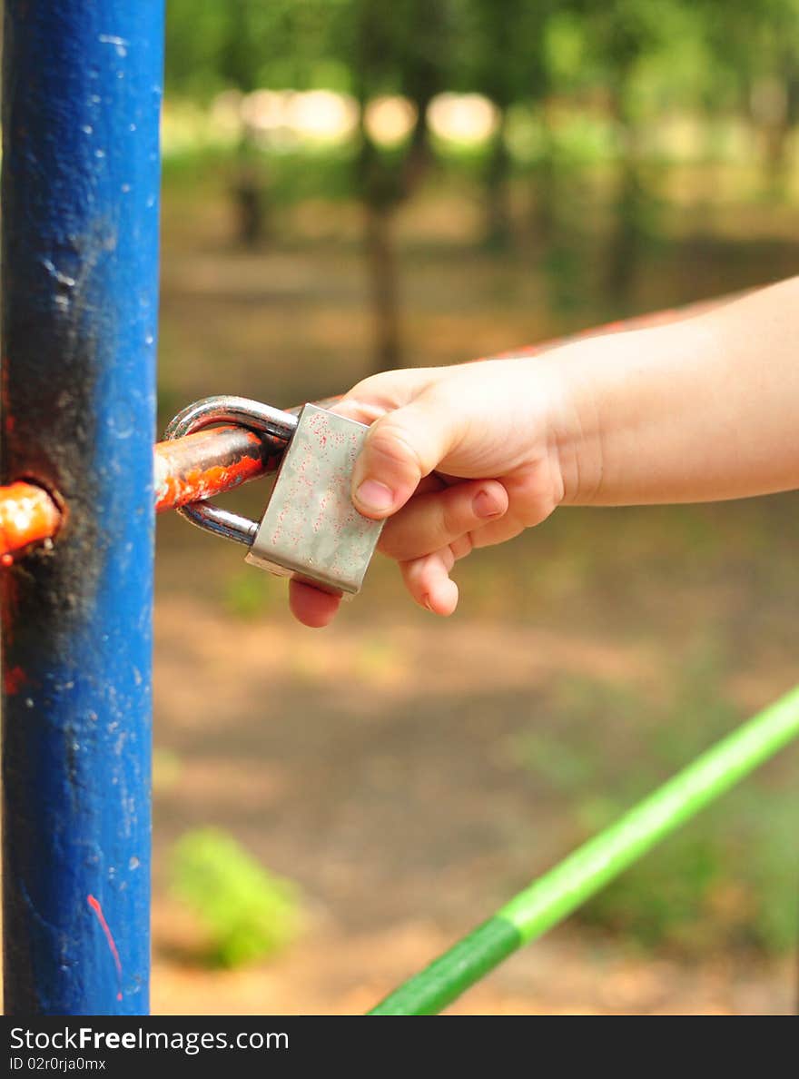 Child's hand touched the closed lock on the lattice