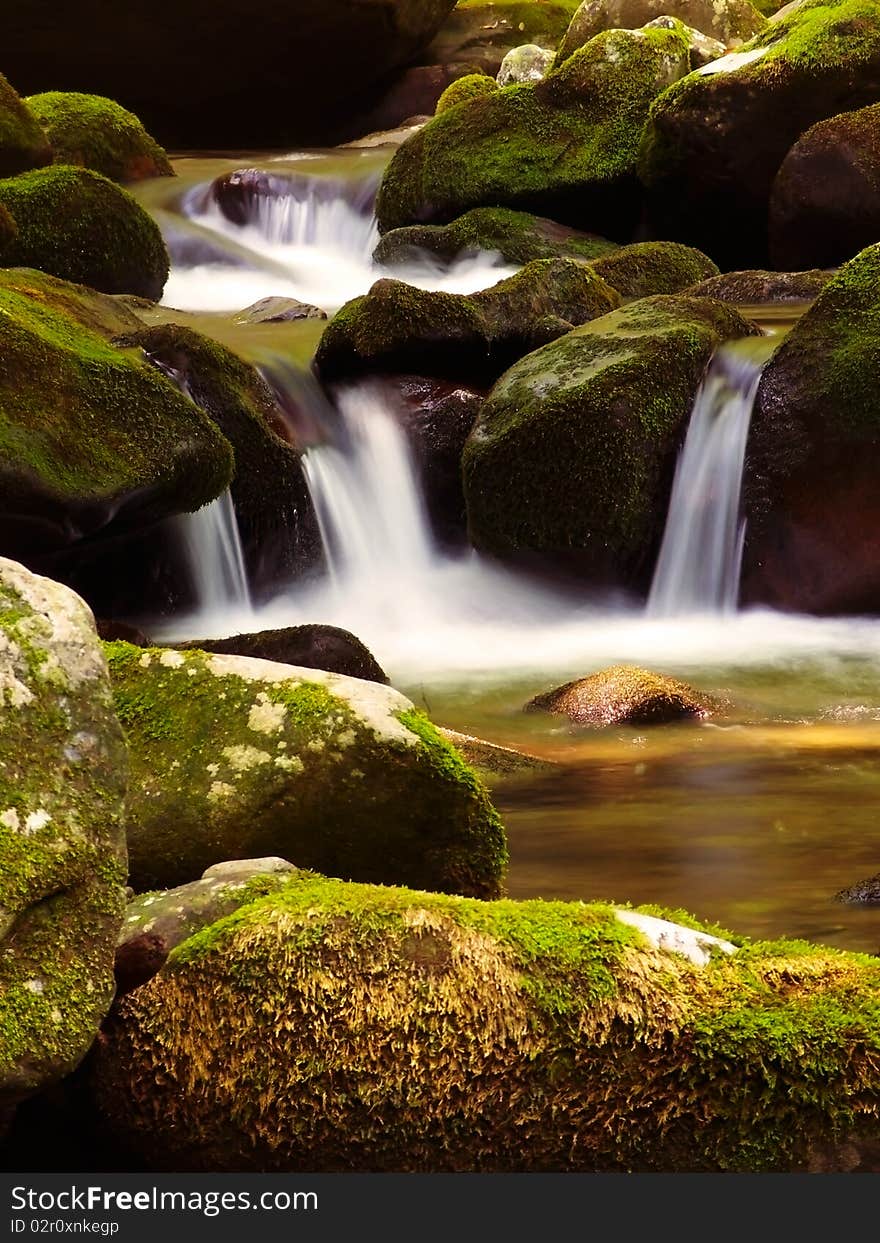 Small stream spilling over some moss-covered rocks. Small stream spilling over some moss-covered rocks.