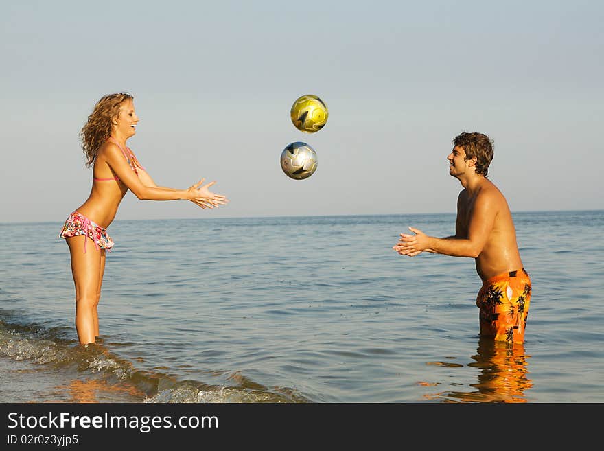 Funny young couple playing balls on the beach. Funny young couple playing balls on the beach