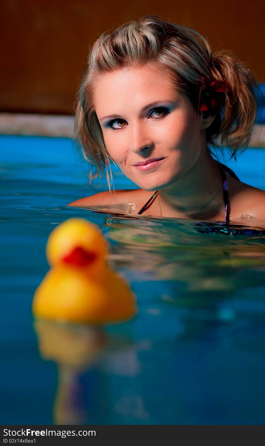 Young girl in pool with yellow duck in front of her. Young girl in pool with yellow duck in front of her