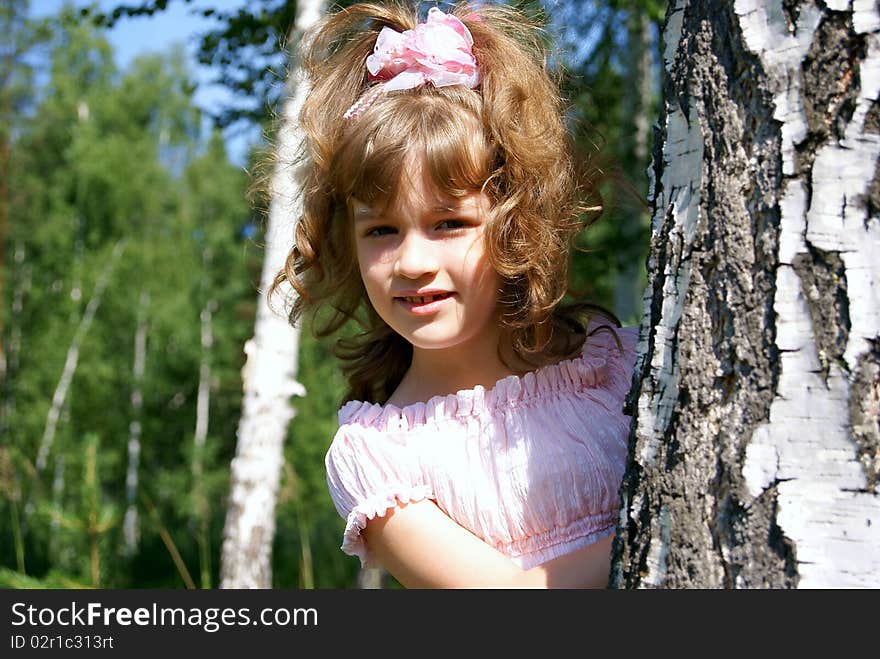 In the summer in park the child looks out because of a tree. In the summer in park the child looks out because of a tree