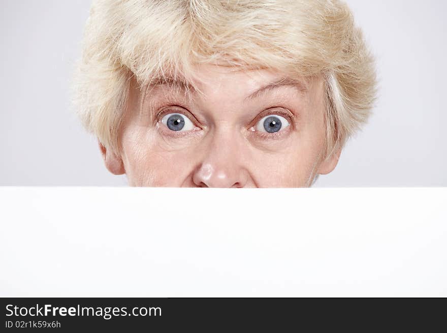 Mature woman with surprised eyes with a blank form closeup. Mature woman with surprised eyes with a blank form closeup