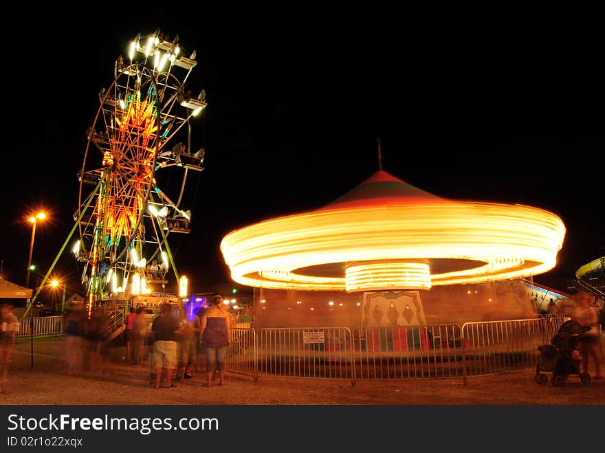 A view of the ferris wheel and merry go around in motion at the county fairgrounds night. A view of the ferris wheel and merry go around in motion at the county fairgrounds night