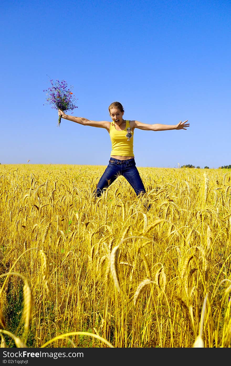 Beautiful smiling girl jumps in the golden field