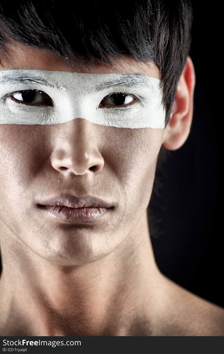 Shot of a stylish young man with painted eyes posing over black background. Shot of a stylish young man with painted eyes posing over black background.