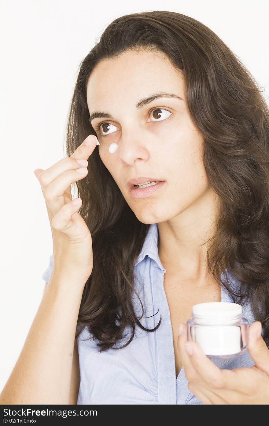 Woman with dark hair applying lotion on her face. Woman with dark hair applying lotion on her face