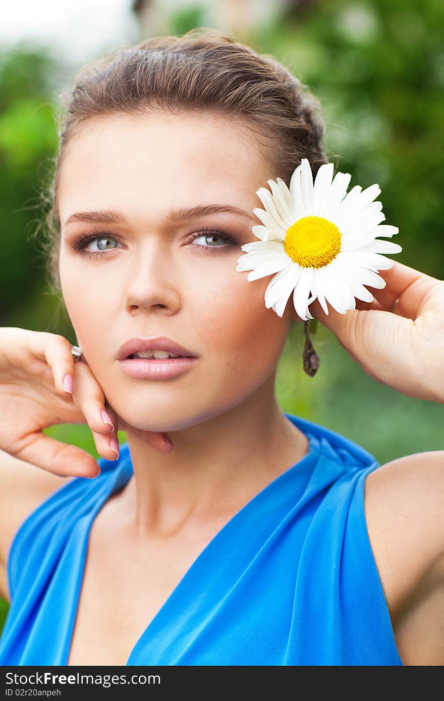 Attractive young lady holding chamomile and looking away. Attractive young lady holding chamomile and looking away