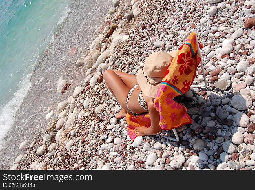 A girl sitting on a sunbed on Adriatic beach in Montenegro. A girl sitting on a sunbed on Adriatic beach in Montenegro