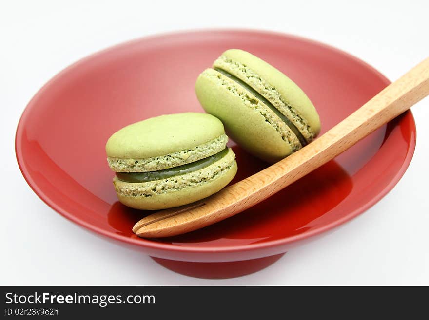 French Macarons served on a red plate with a wooden fork on white background. French Macarons served on a red plate with a wooden fork on white background.