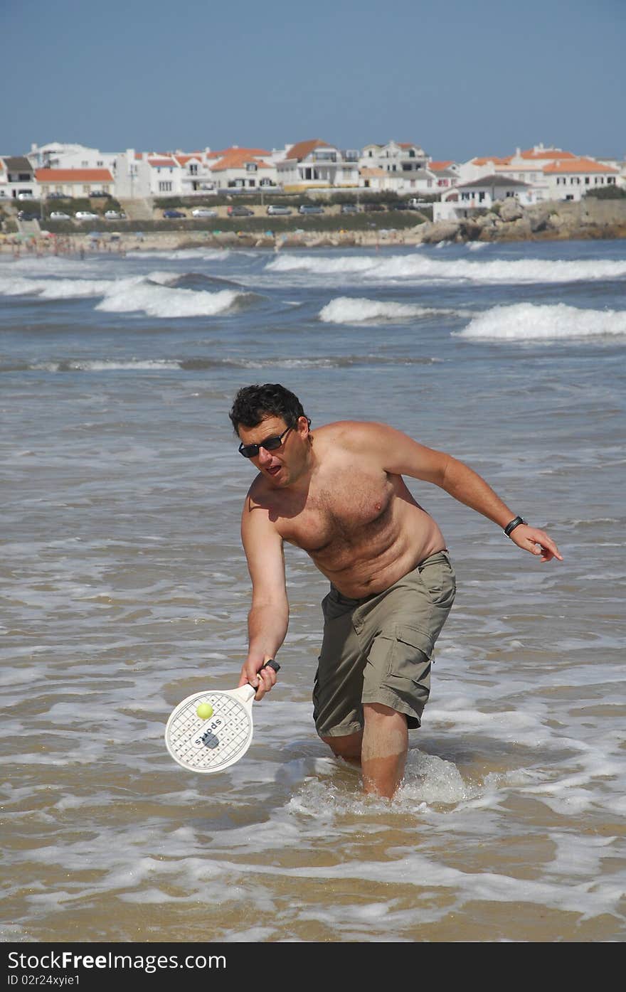 A fat man playing beach tennis on the beach