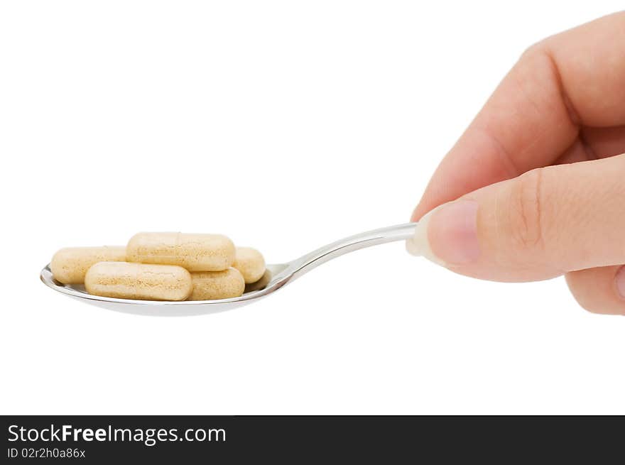 Pills in a spoon isolated on white background